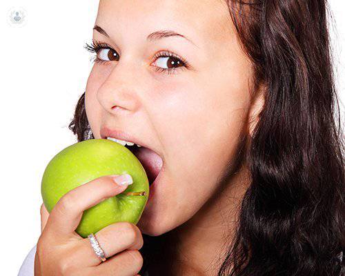implantes-dentales-chica-mordiendo-manzana-boca-sana